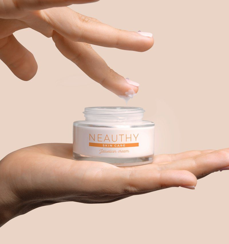 Hand holding an open jar of cream